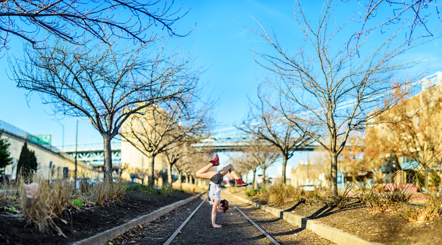 A woman stands on her hands in the middle of delaware ave in philadelphia.